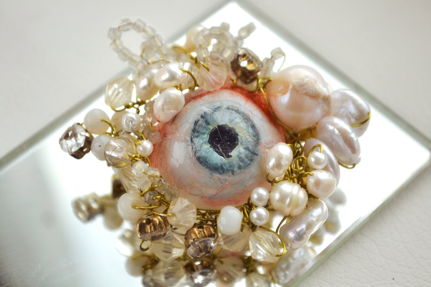 Artificial eye surrounded by pearls and beads brooch by Polina Verbytska, Witness III
