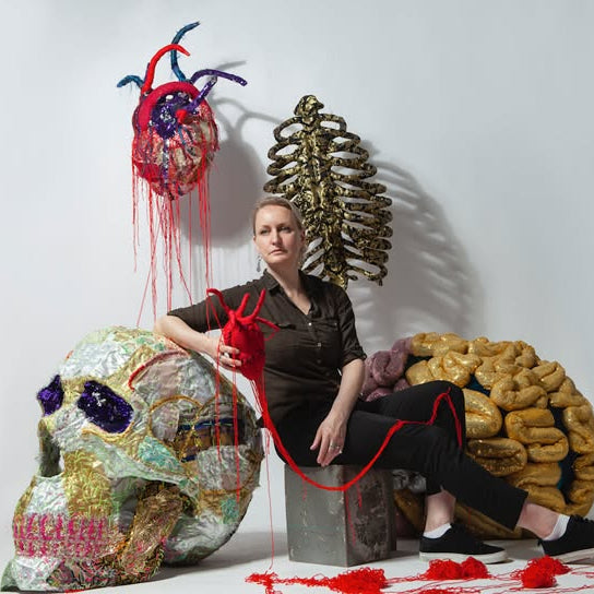 Woman sitting on a concrete block with artistic sculptures around her.
