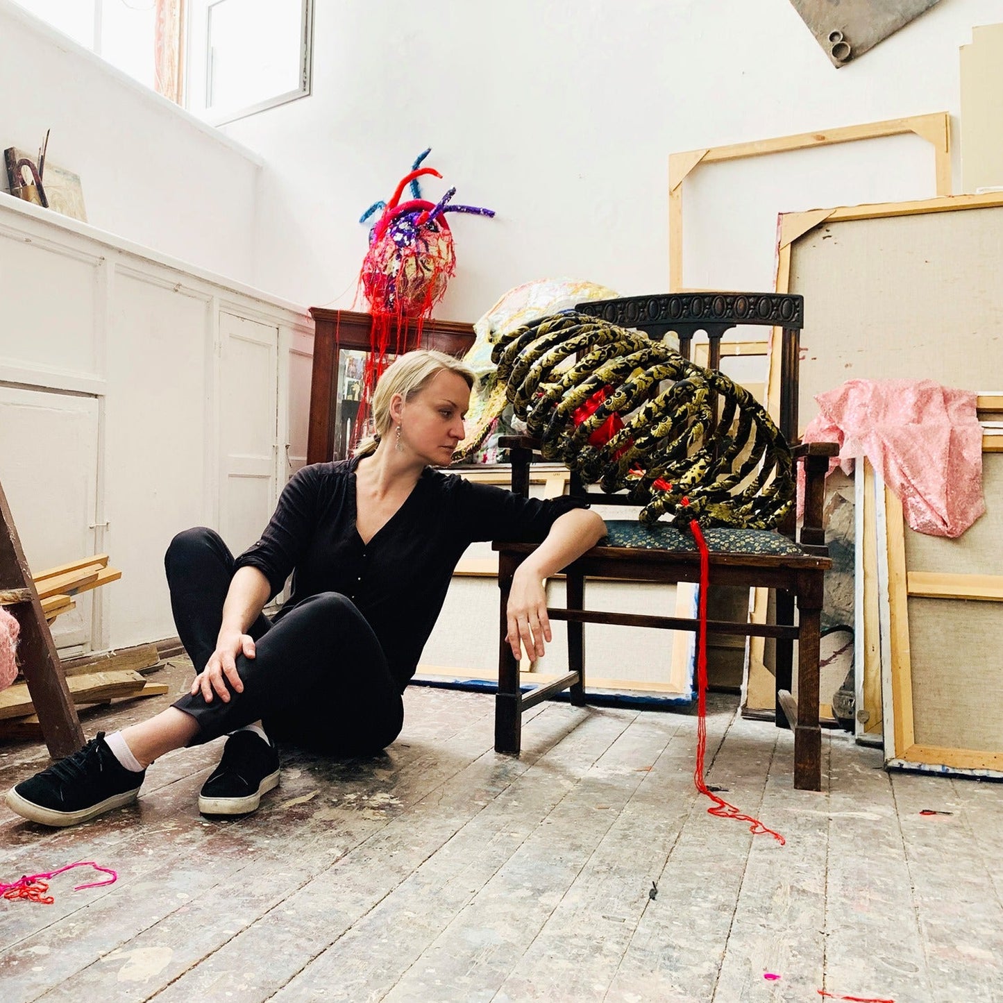 Person sitting on a chair in a room with large yellow ropes and various objects around