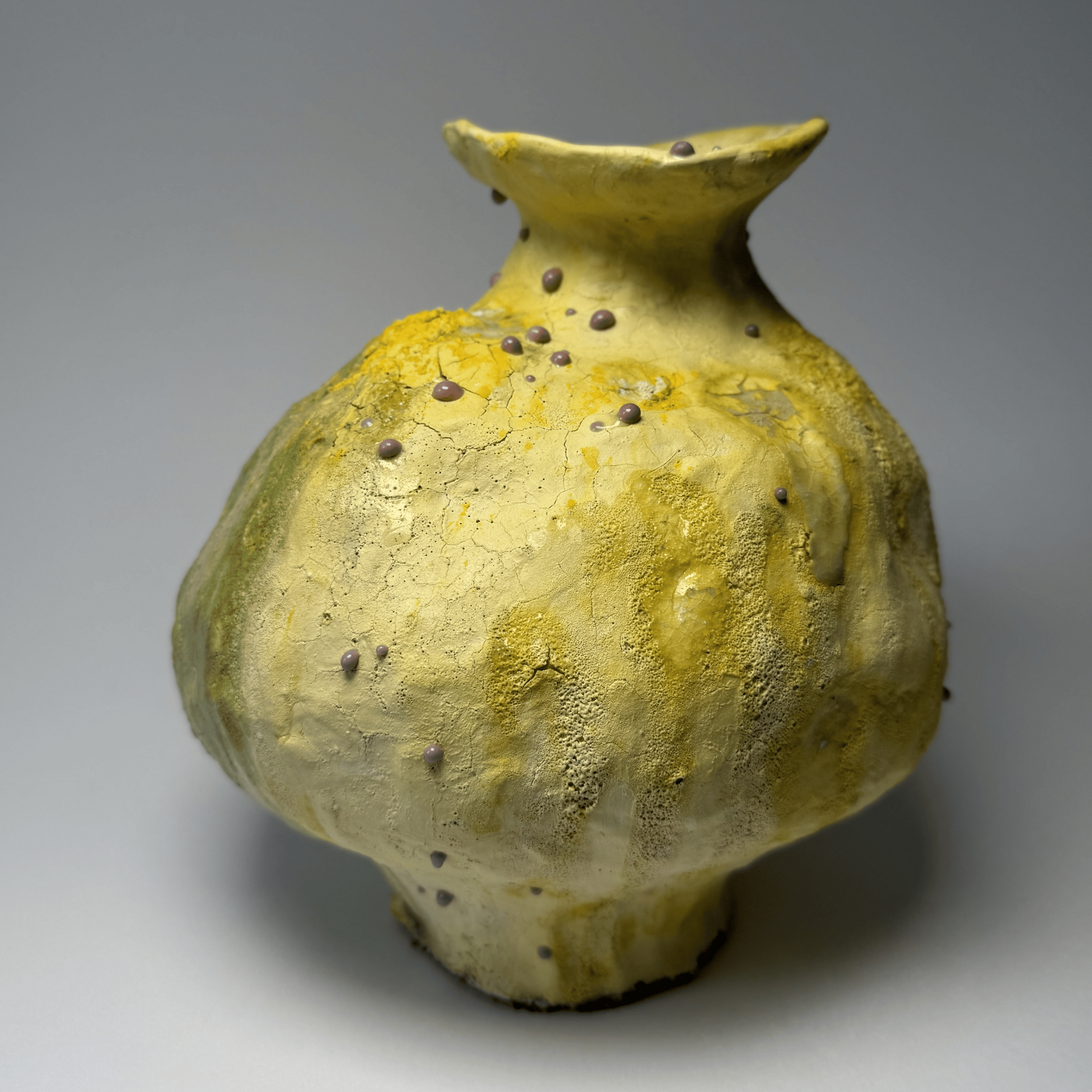 Yellow ceramic vase with textured surface on a gray background