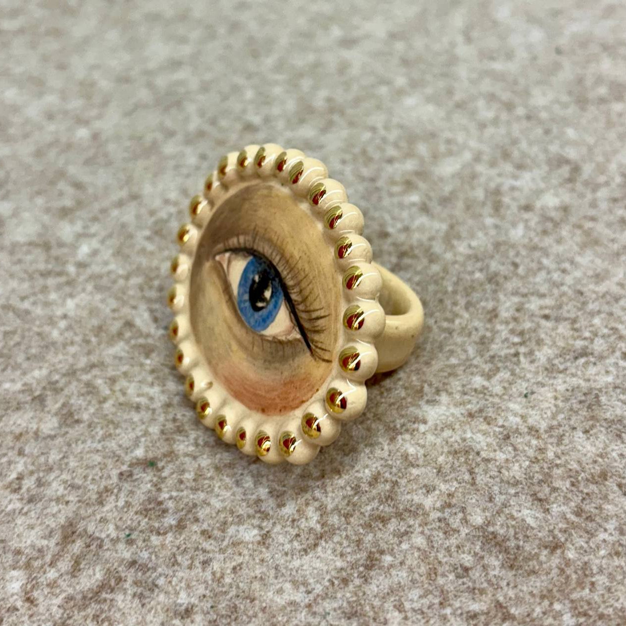 Gold ring with eye design on a textured surface