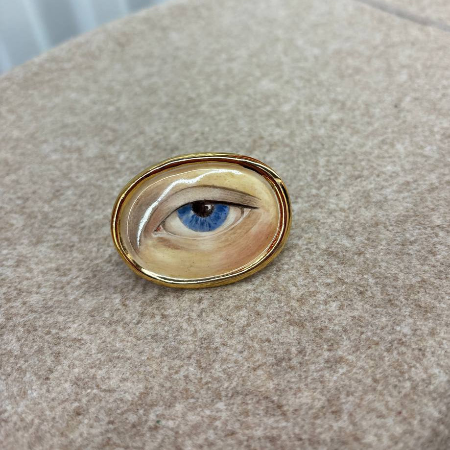 Ring with a detailed painting of an eye on a textured surface