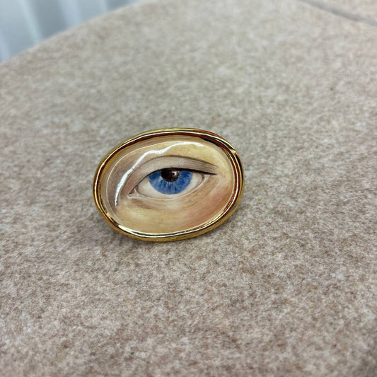 Ring with a detailed painting of an eye on a textured surface
