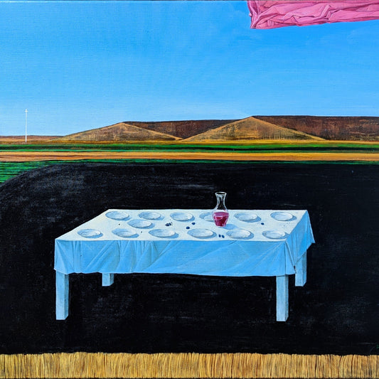 Table with blue tablecloth and white plates set against a landscape with hills and blue sky.
