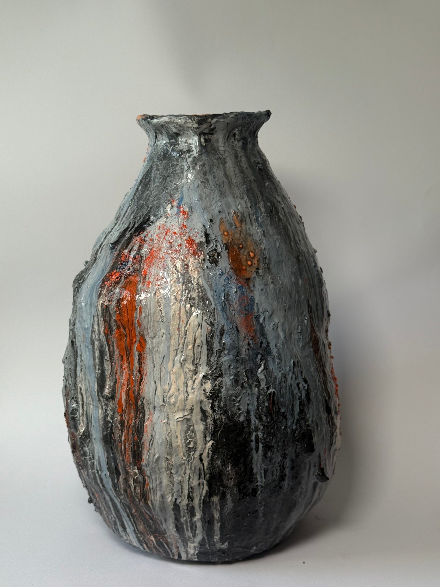 Textured ceramic vase with orange and black patterns on a white background