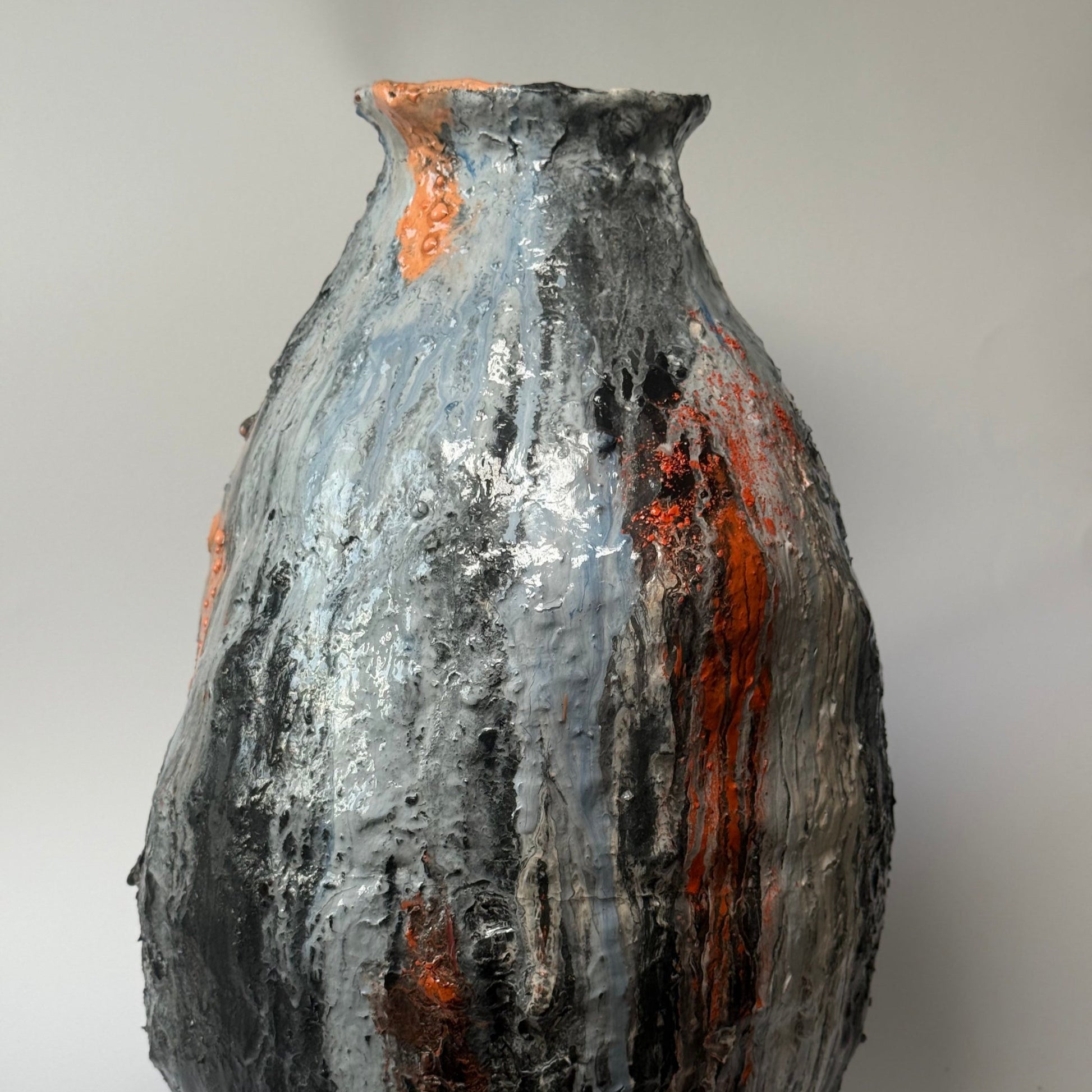 Textured ceramic vase with orange and black patterns on a white background