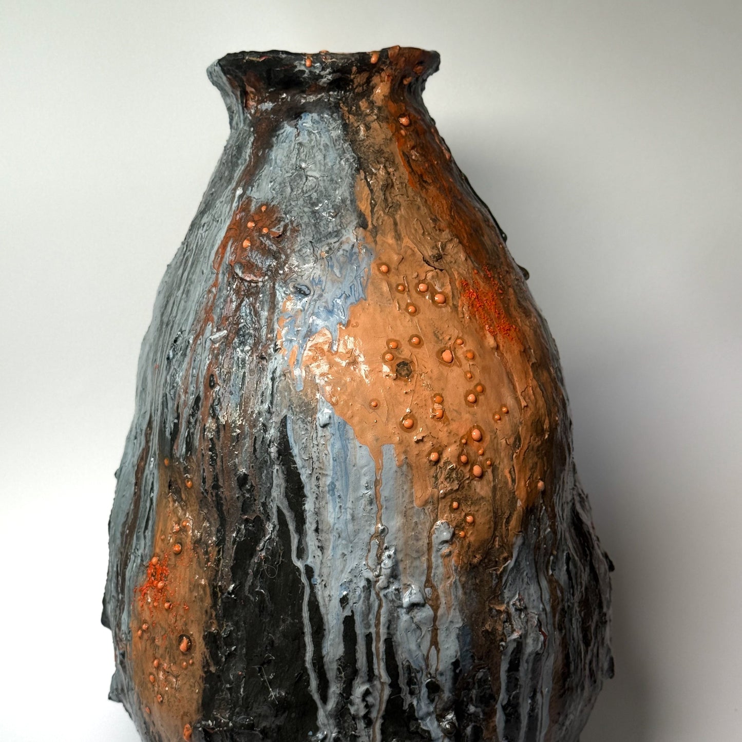 Textured ceramic vase with orange and black patterns on a white background