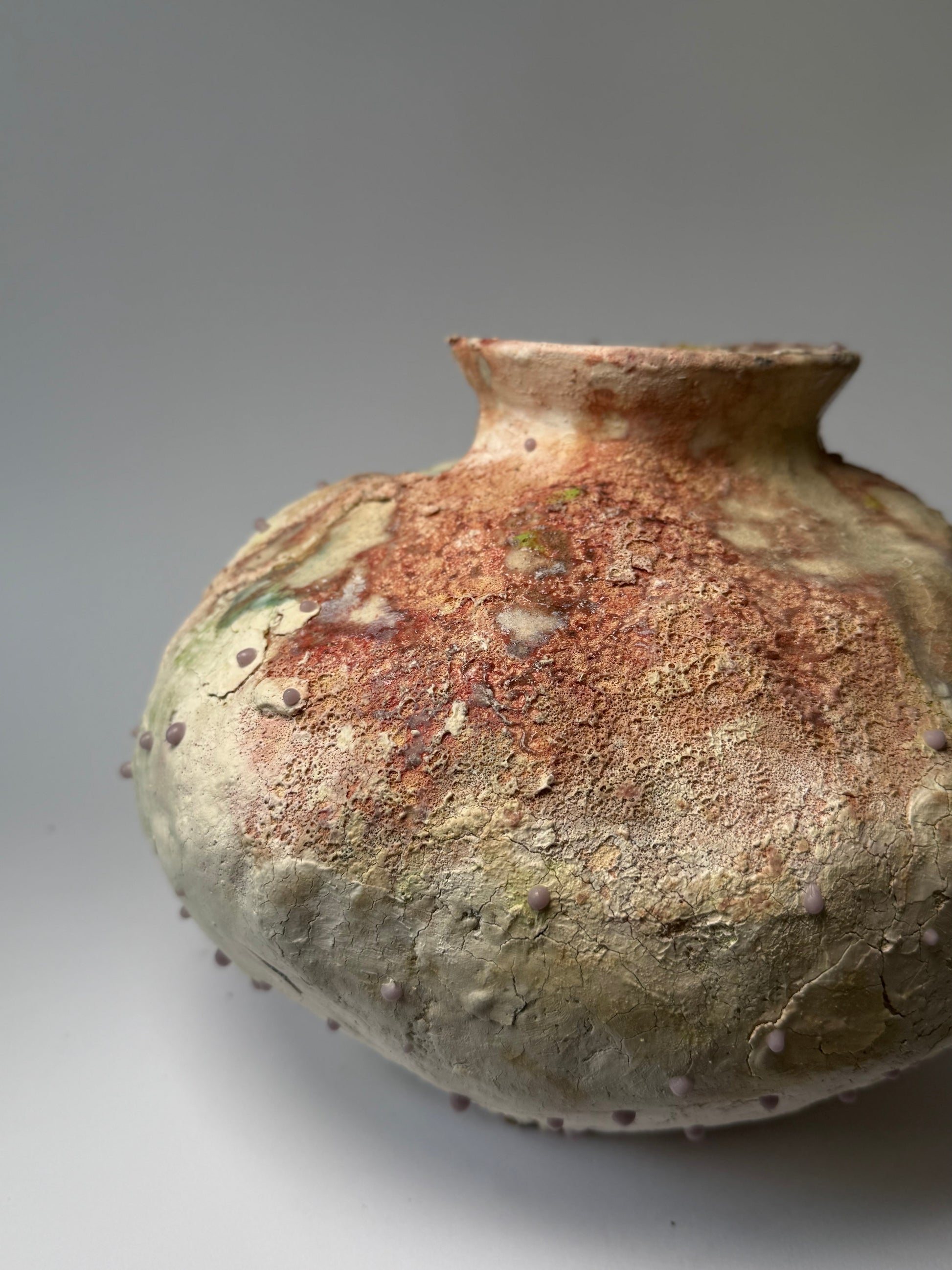 Close-up of decorative ceramic vase with textured surface on a gray background