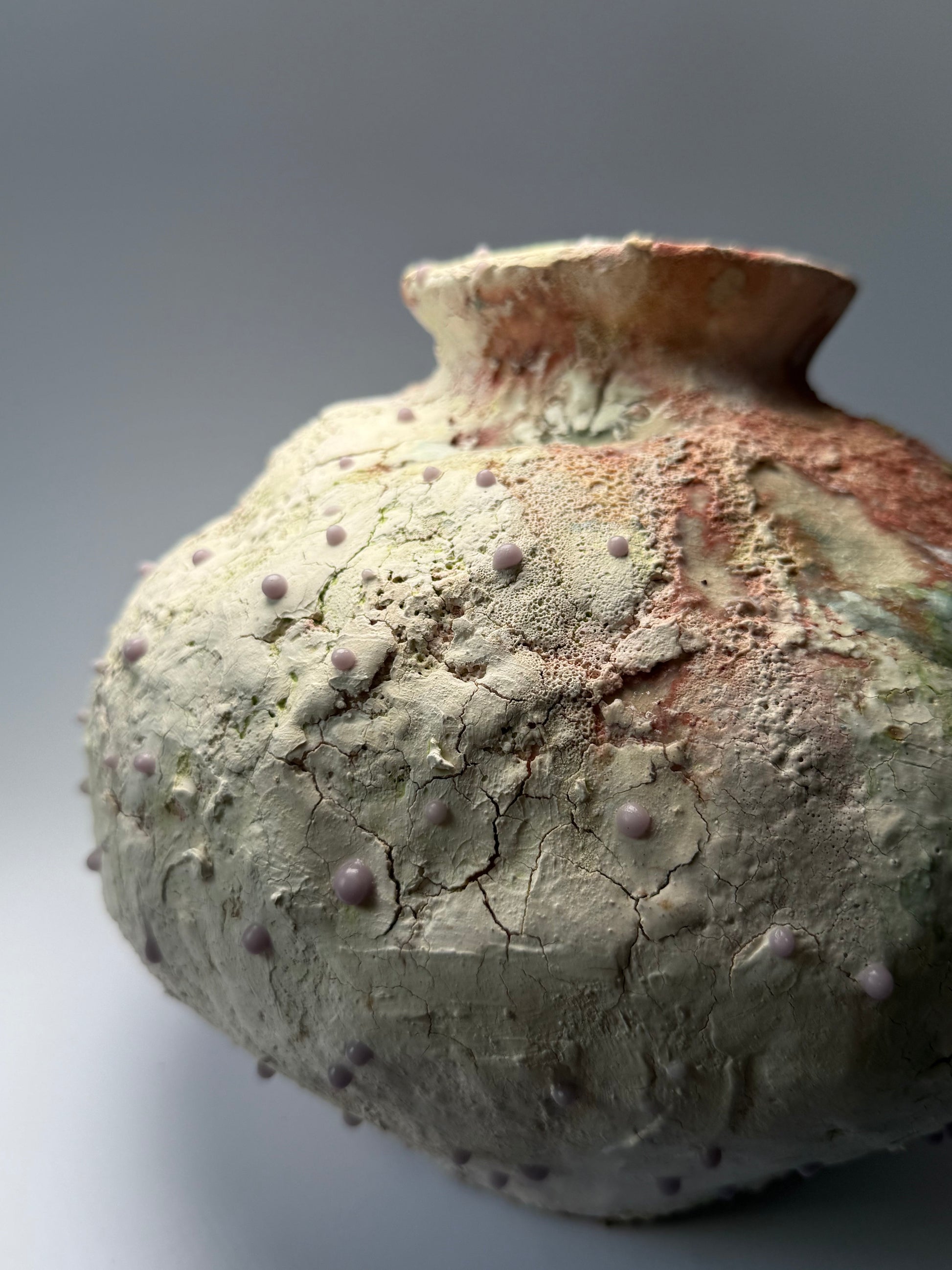Close-up of decorative ceramic vase with textured surface on a gray background