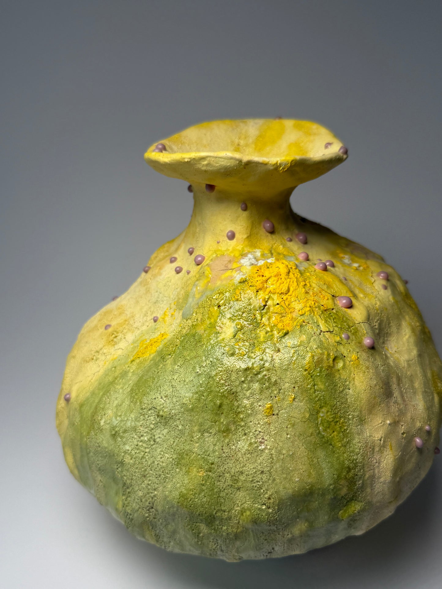 Green ceramic vase with textured surface on a gray background