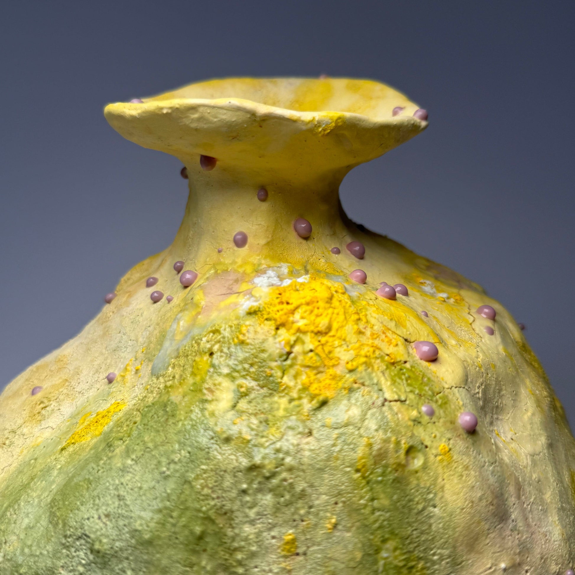 Close-up of a yellow textured ceramic vase with a dark background