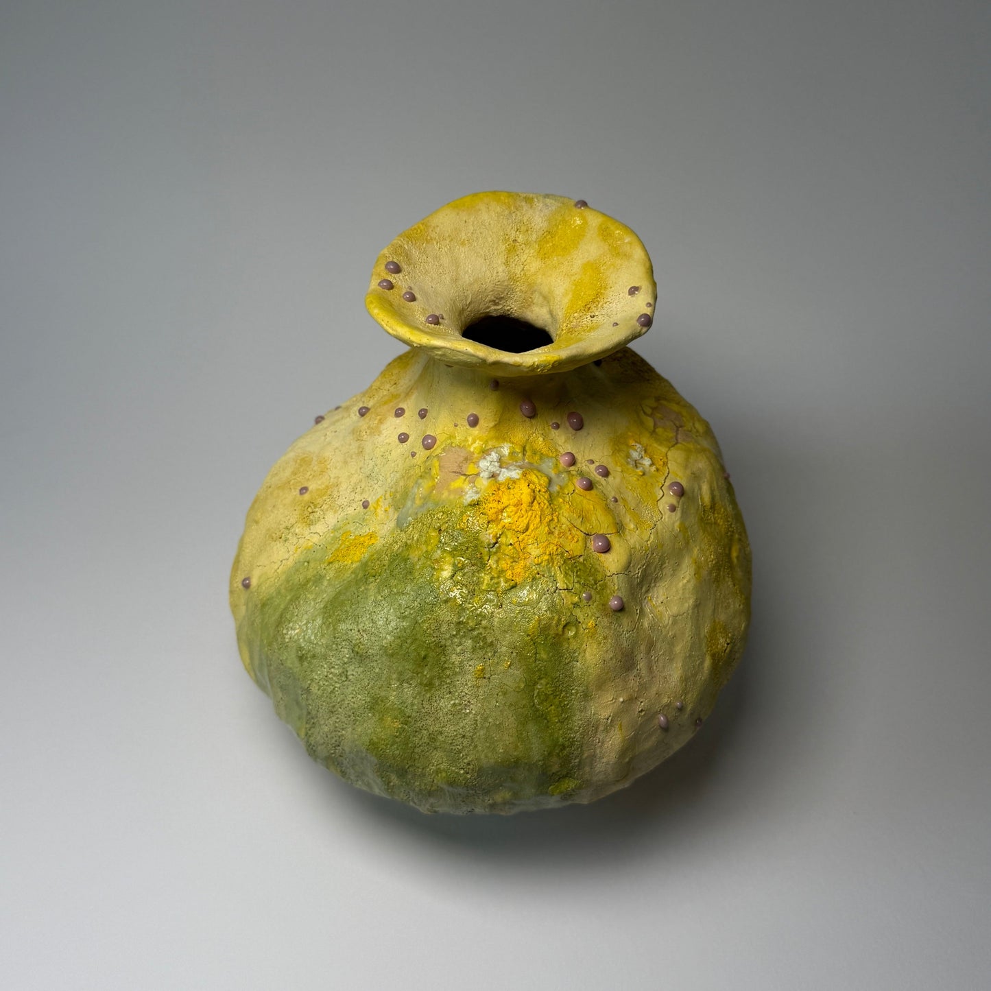 Yellow and green ceramic vase on a gray background