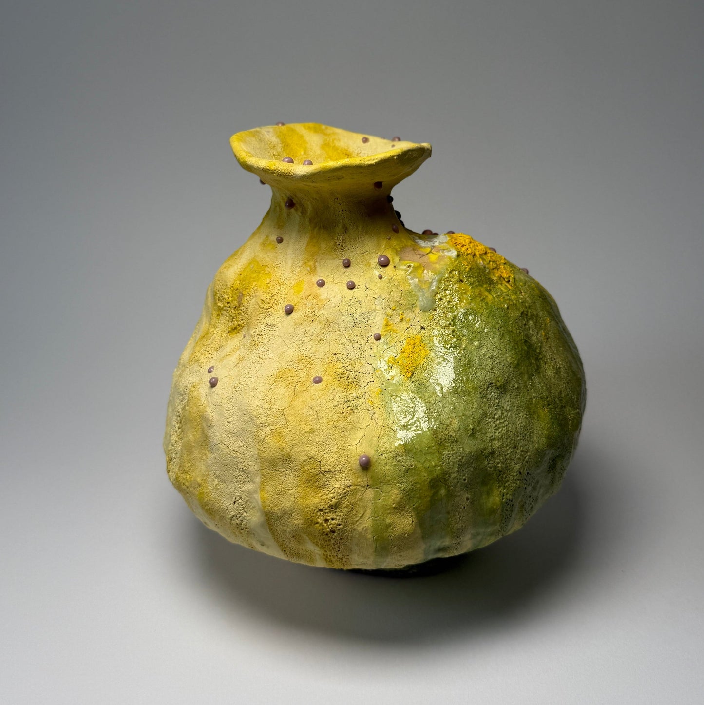 Vintage green ceramic vase with yellow top on a gray background