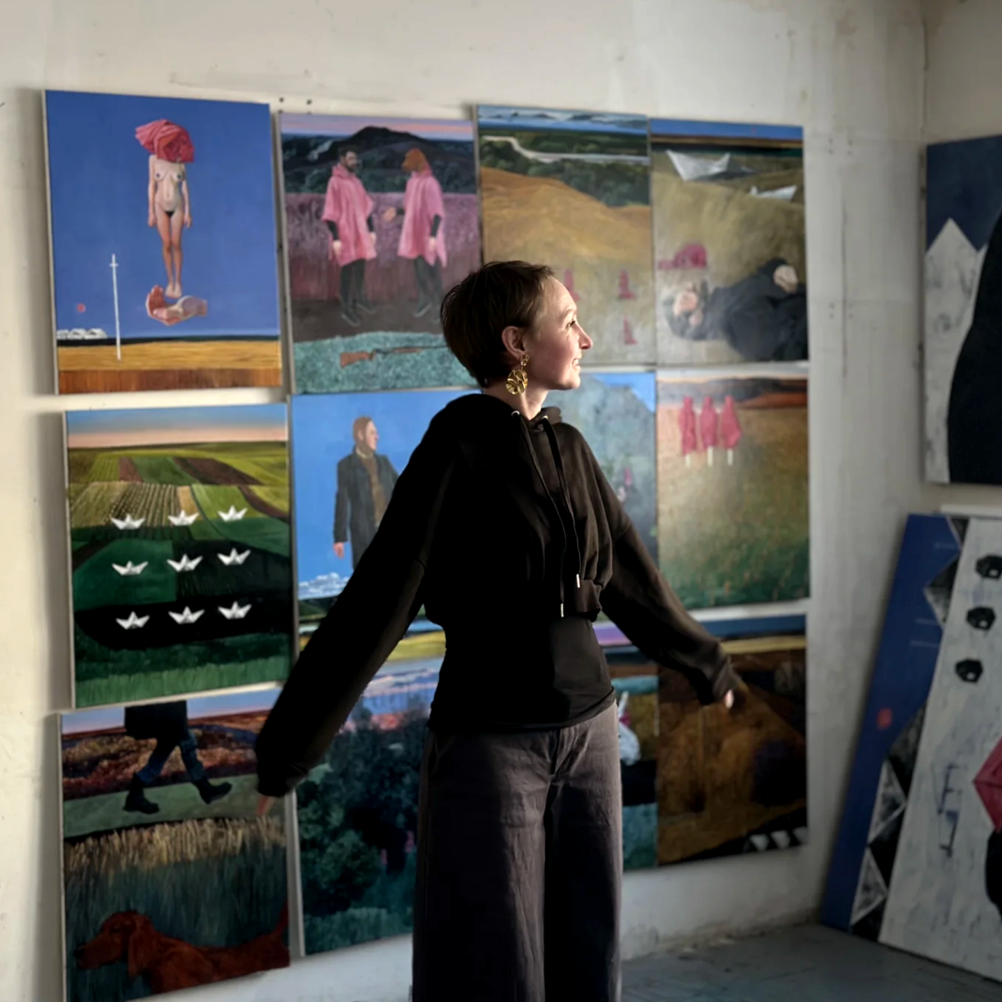 Polina Kuznetsova is standing in front of a wall with her paintings