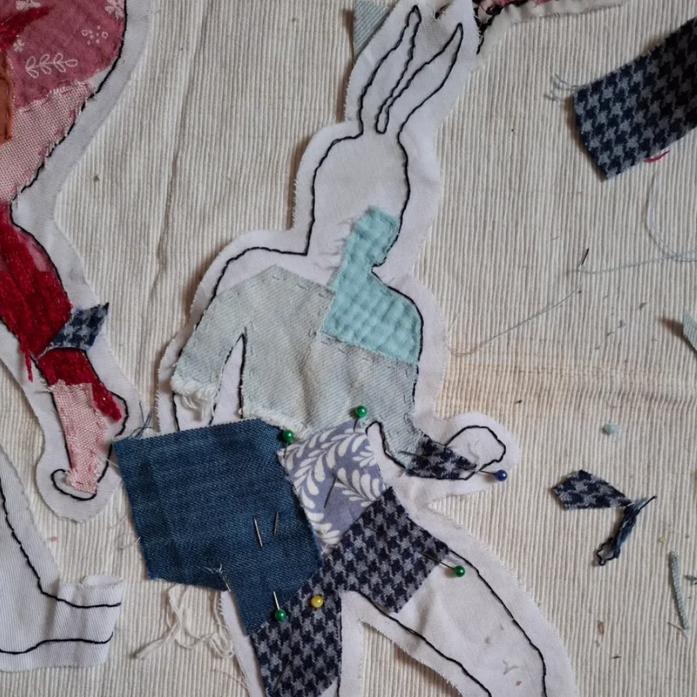 Collage of a figure made from various fabric pieces on a textured surface