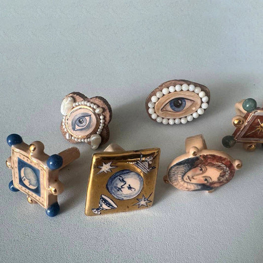 Collection of decorative rings with artistic designs on a light gray background
