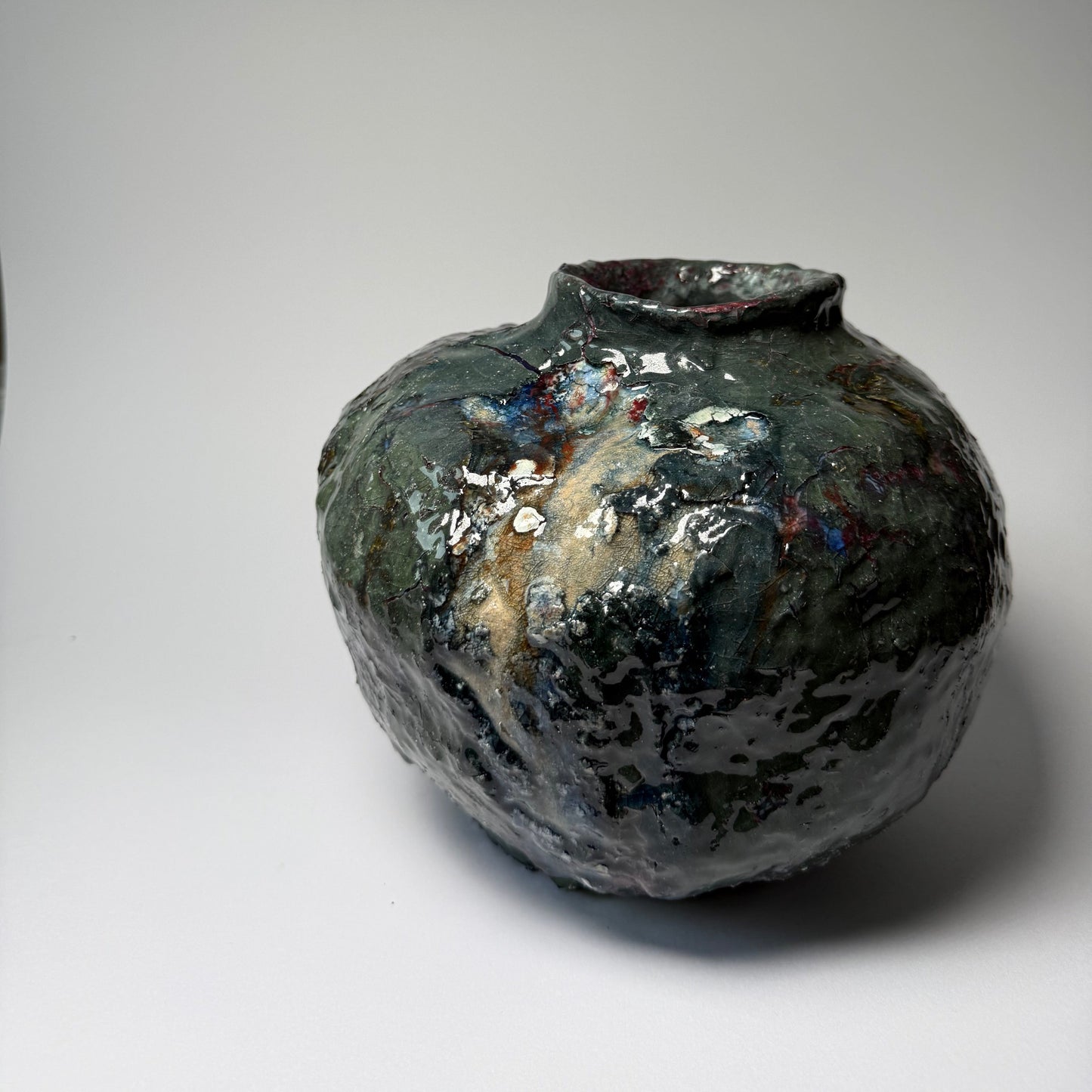 Black textured ceramic vase with a textured surface on a light gray background