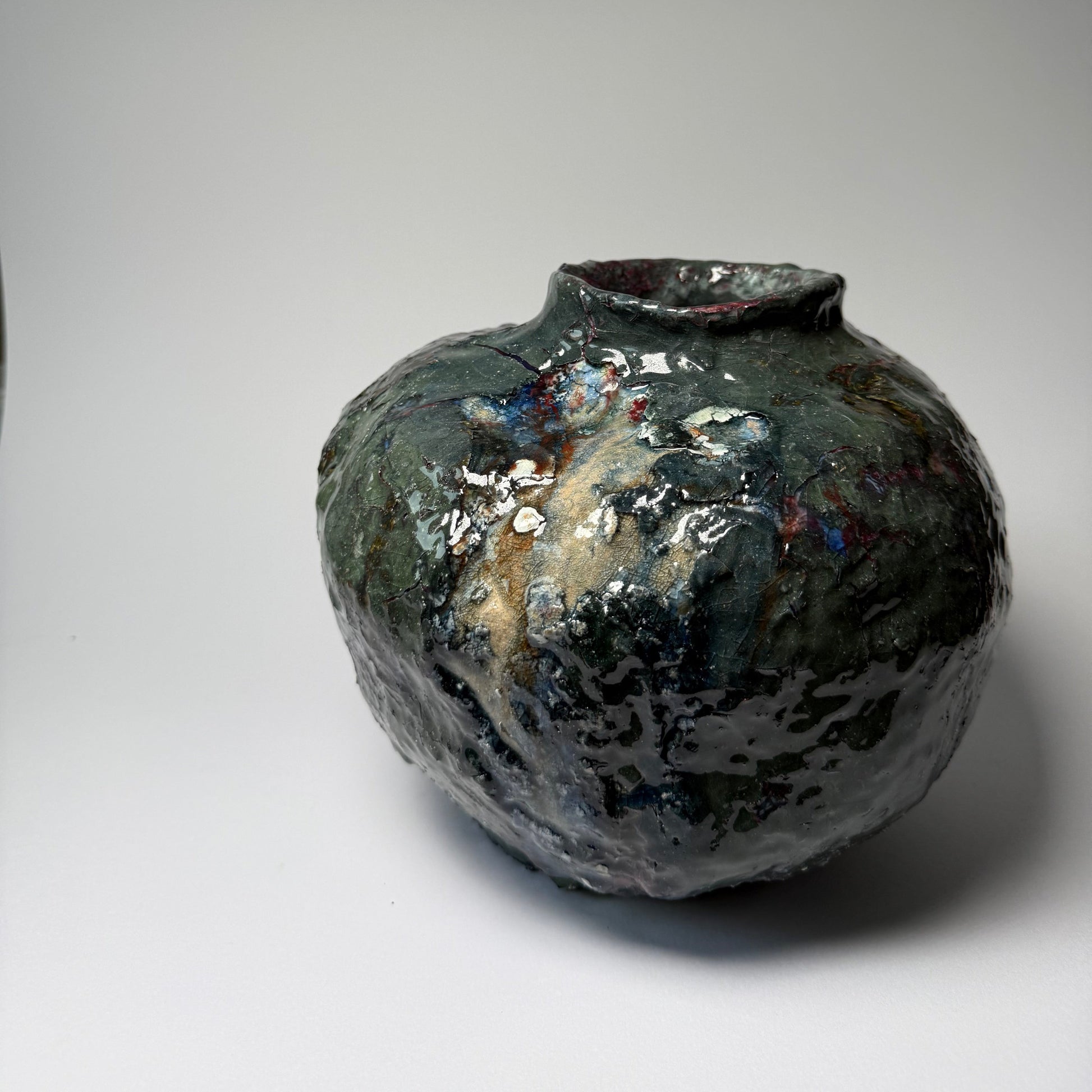 Black textured ceramic vase with a textured surface on a light gray background