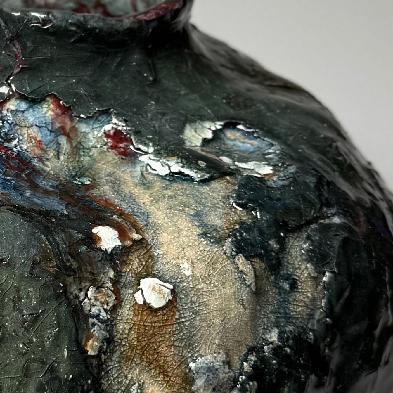 Close-up of a textured green modern ceramic vase with a mottled surface.