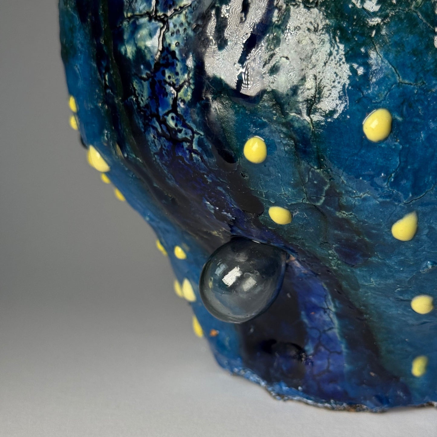Close-up of a blue vase with yellow spots on a gray background