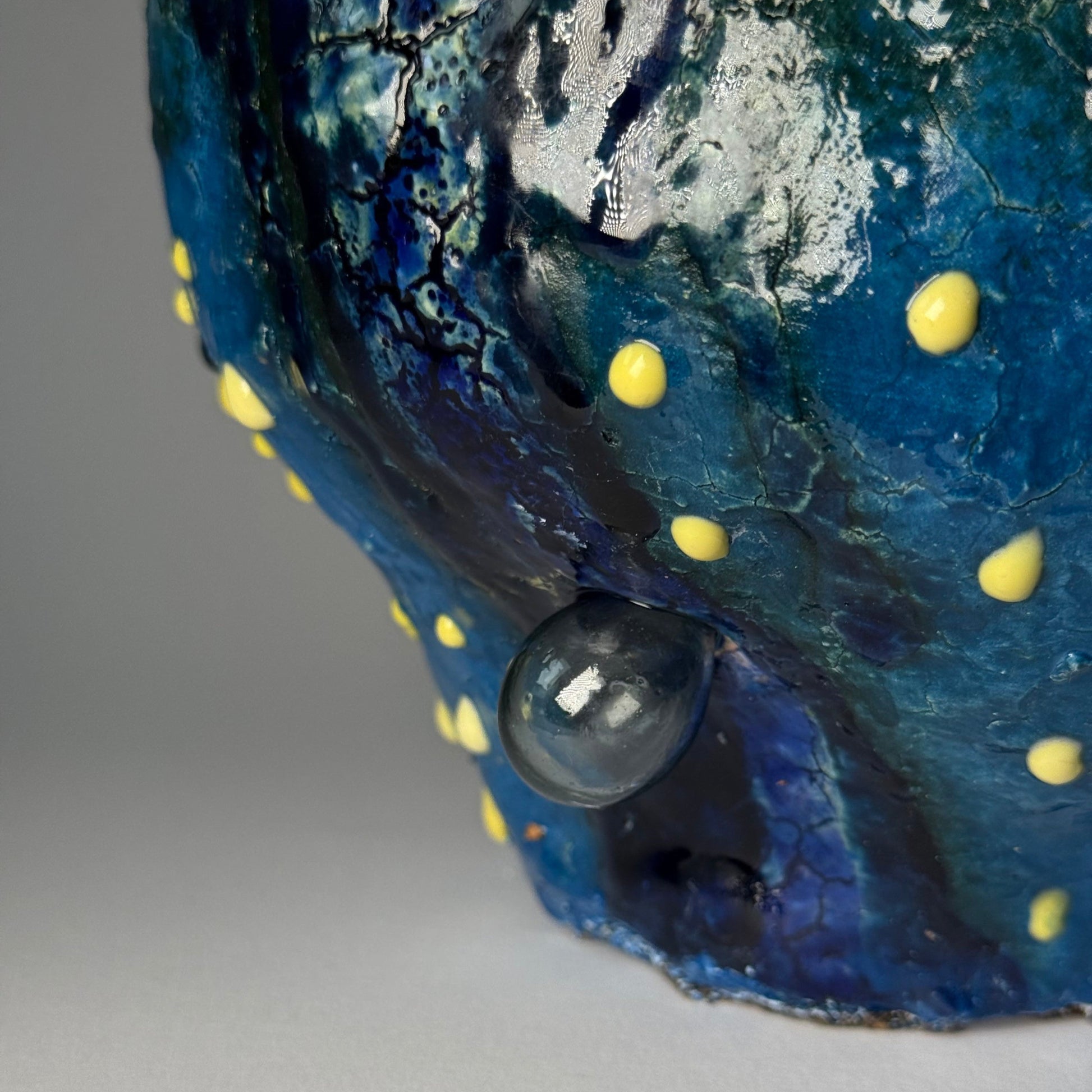 Close-up of a blue vase with yellow spots on a gray background