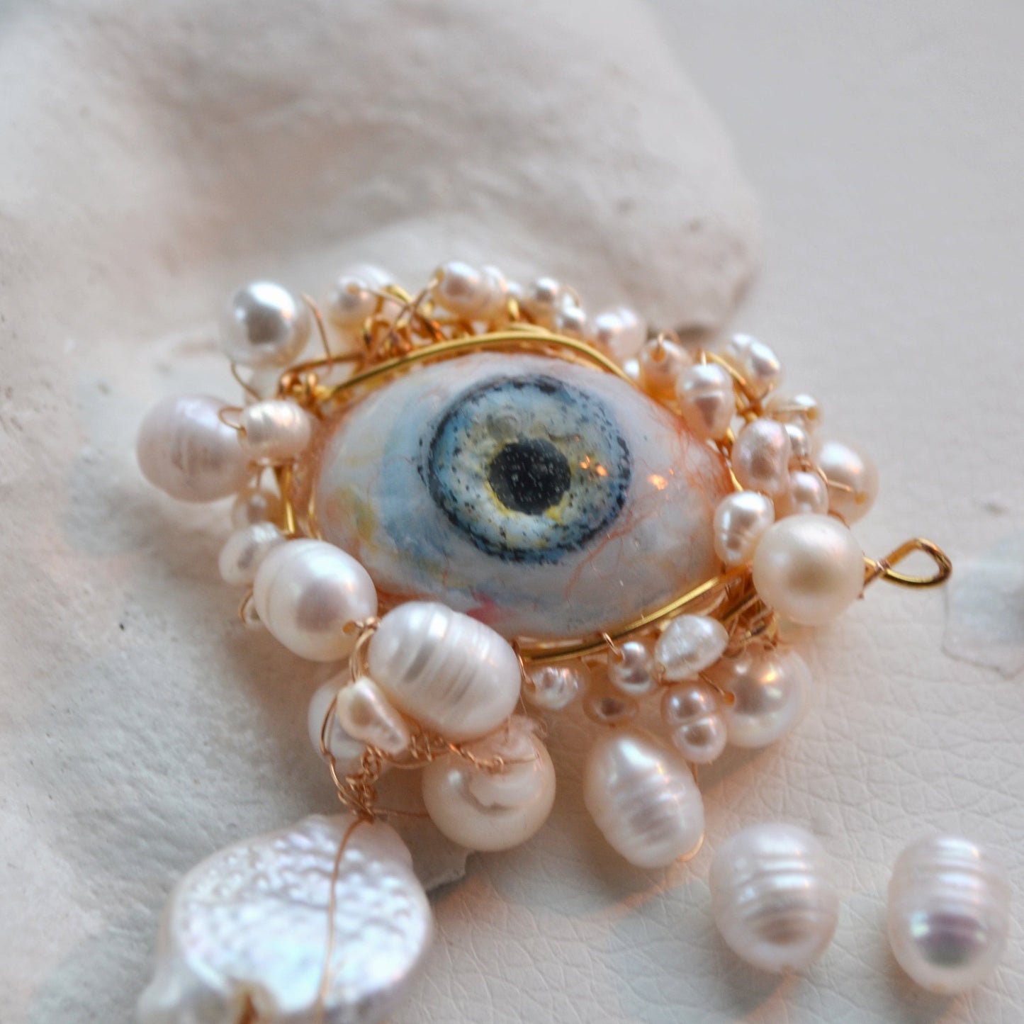Pearl and gold brooch on a textured white surface