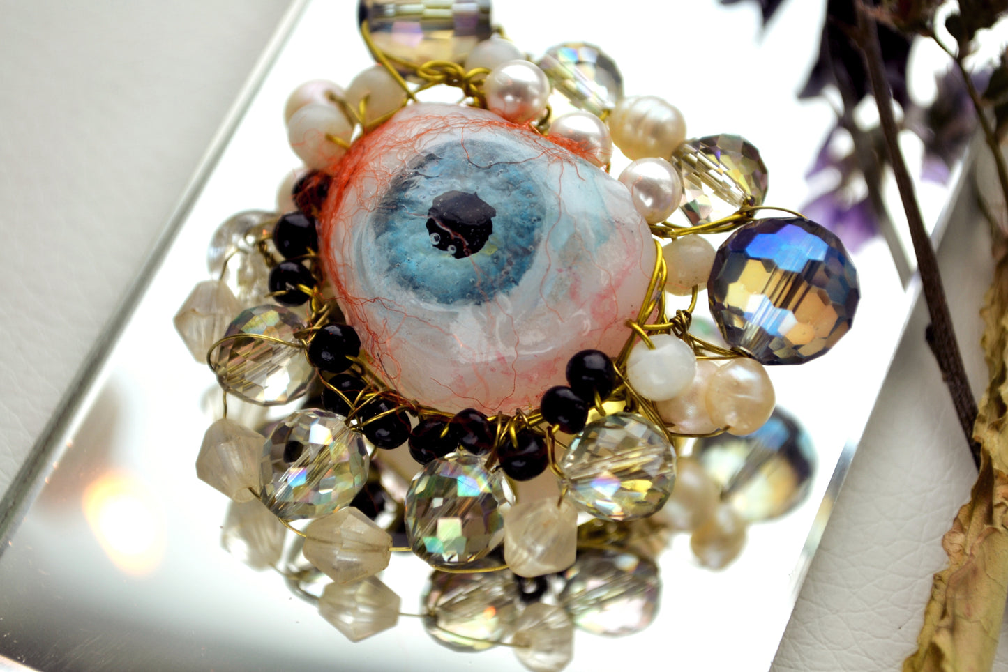 Brooch with multicolored beads and a central eye-shaped pendant on a white background