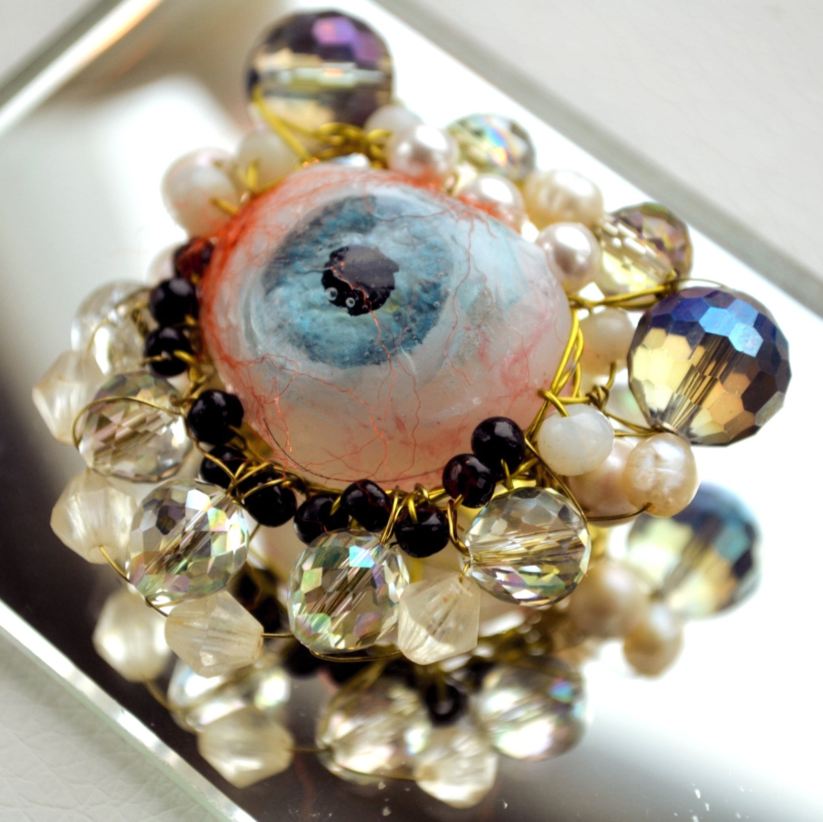 Decorative brooch with multicolored beads on a mirror surface