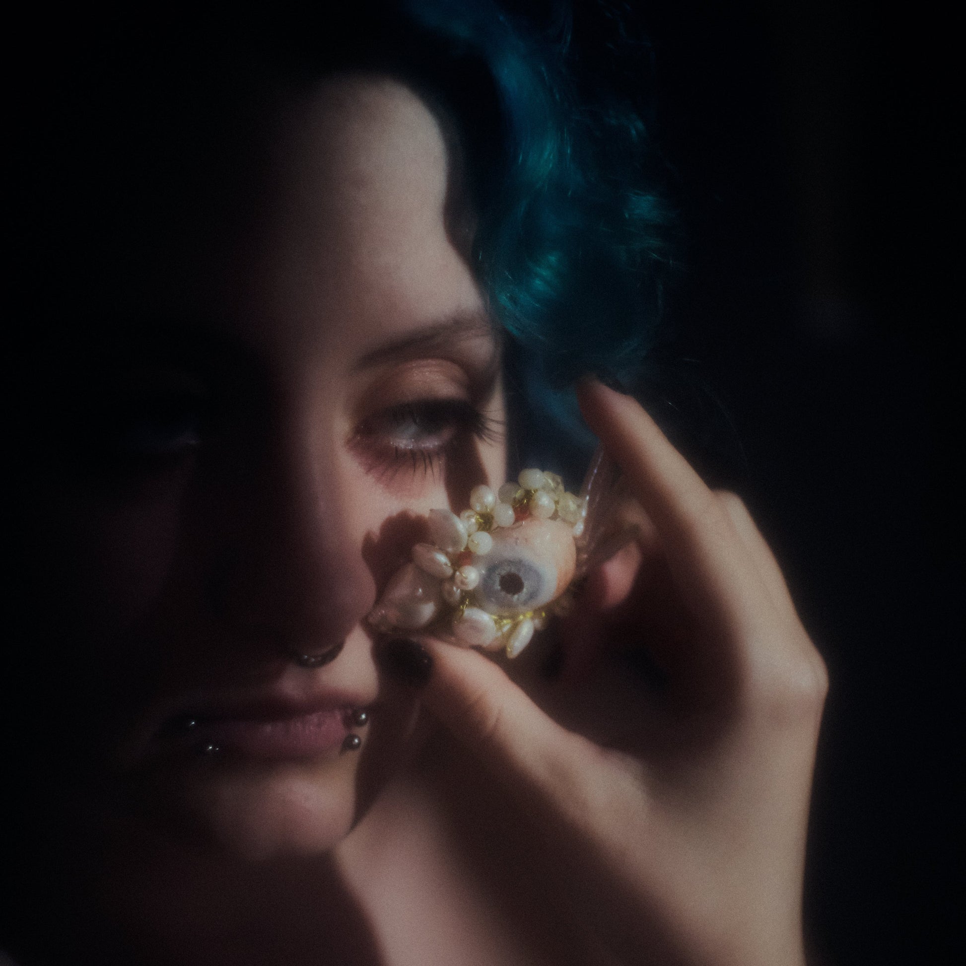 Person holding a decorative object near their face against a dark background