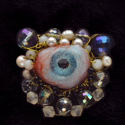 Decorative brooch with beads and gemstones on a dark background