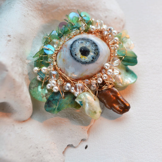 Decorative brooch with gemstones and pearls on a shell background