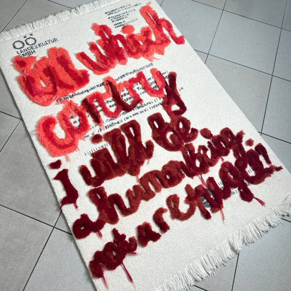 Textile with red and black text on a white background, displayed on a tiled floor.