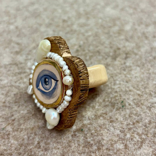 Ring with eye design and pearl beads on a textured surface