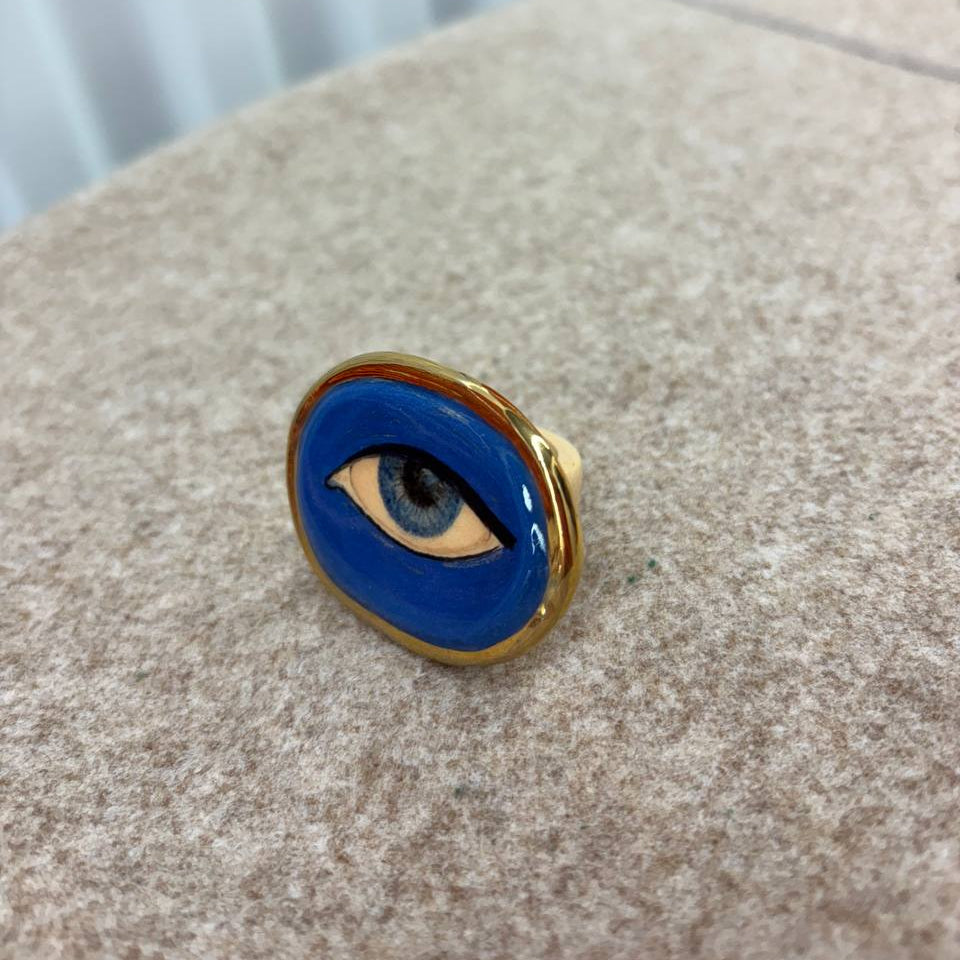 Blue eye-shaped pin on a textured surface with a blurred background