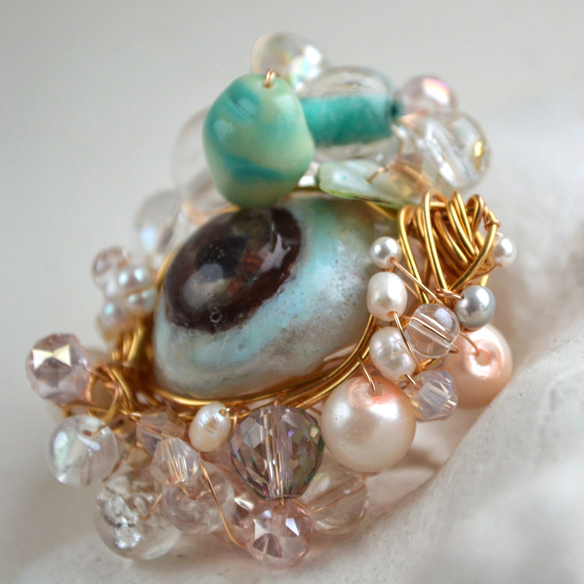 Close-up of a decorative brooch with beads and gemstones on a white background