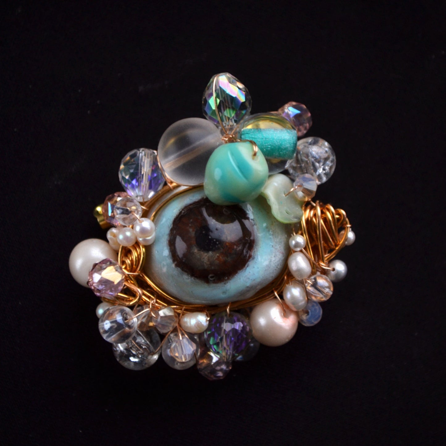 Decorative brooch with gemstones and pearls on a black background