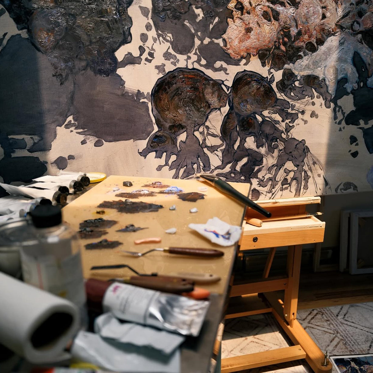 Artistic workspace with painting materials and a canvas featuring animal figures.