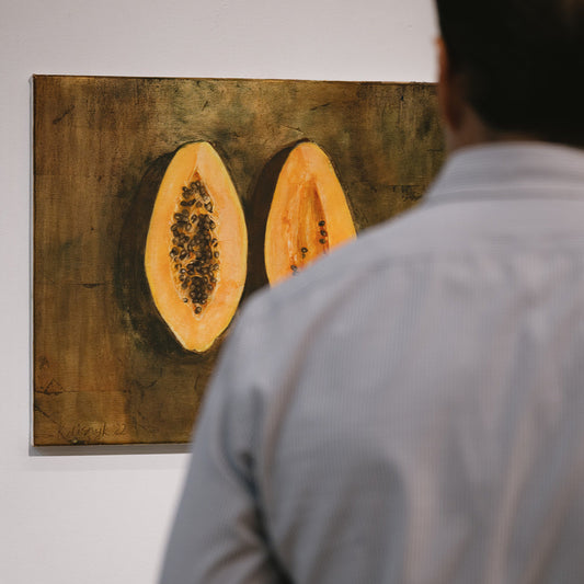Person looking at a painting of a halved papaya on a wall.